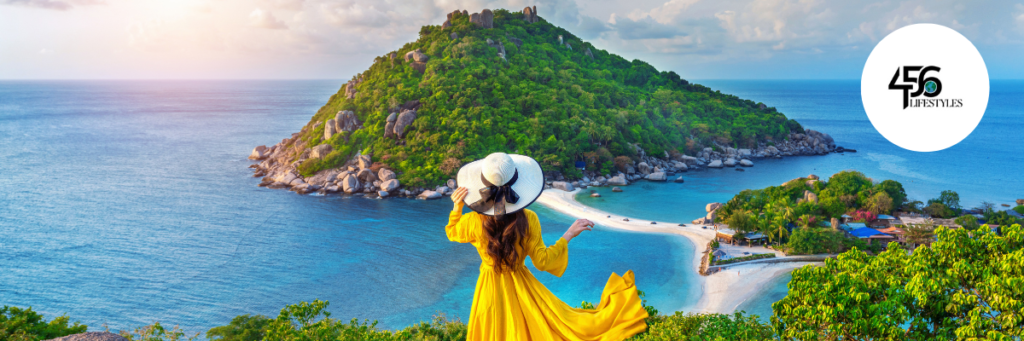 a woman in a yellow dress and hat looking at a beach