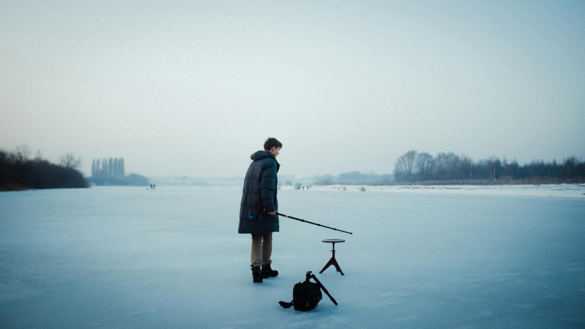 teenager with fishing rod on frozen lake